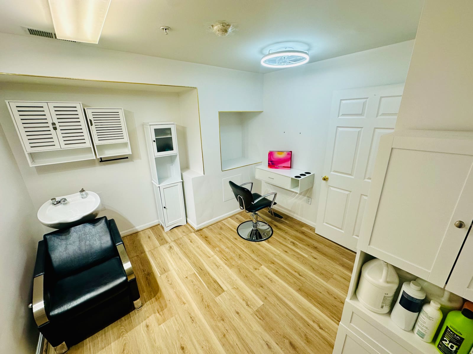 Private salon suite with shampoo bowl, styling station, mirrors, and cabinets